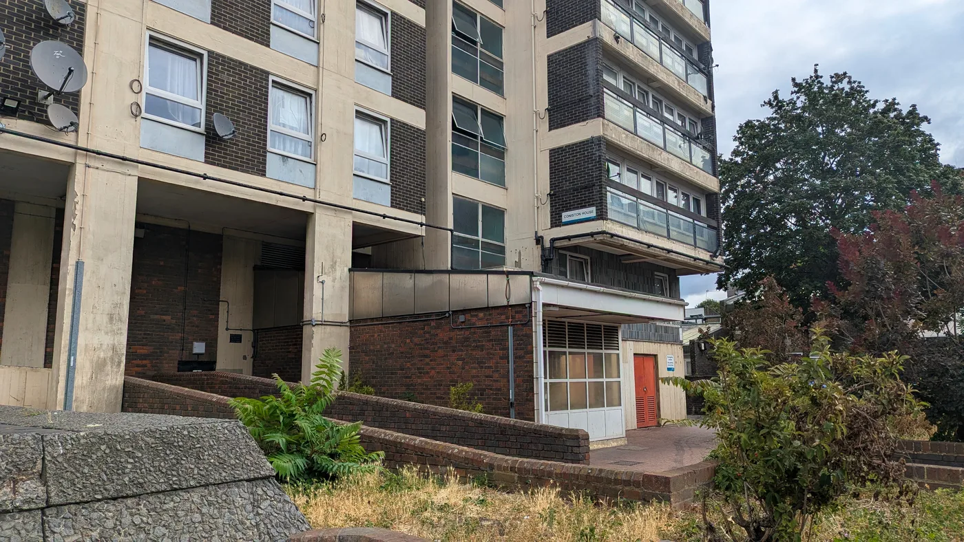 Coniston House, an ex-council block with glazed balconies and a ground-floor entrance in SE5, south London