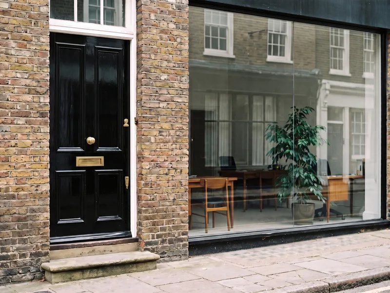 A separate black front door to the flats above, beside the large single-pane window of a ground-floor office