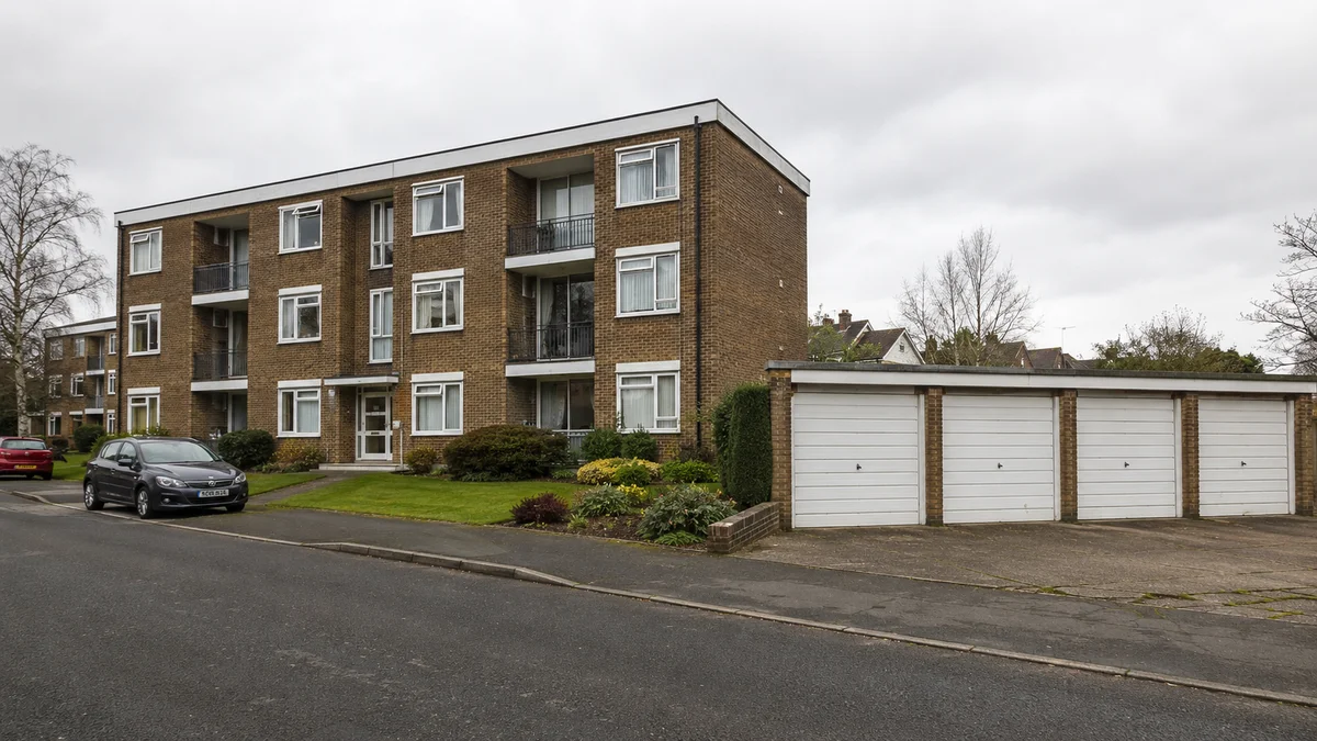 Three-storey purpose-built block of flats in outer London with lock-up garages alongside