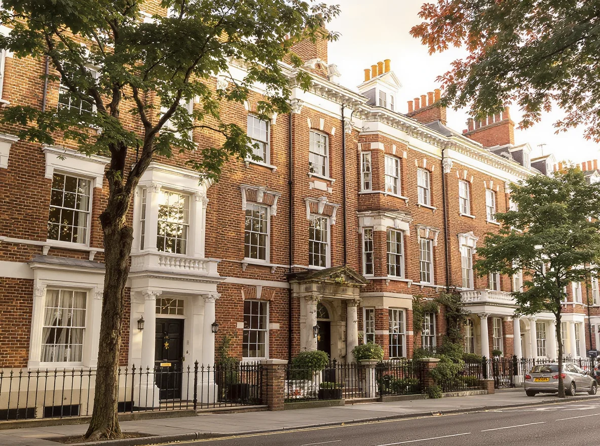 A row of London leasehold flat buildings of different periods on a tree-lined residential street